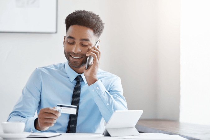 homem atendendo telefone com cartão na mão